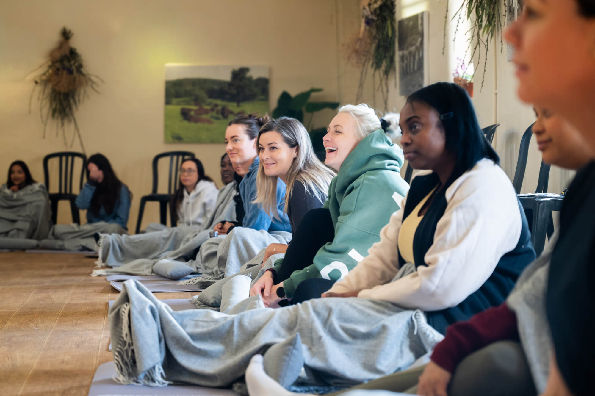 A female corporate group sit together on the floor looking at the guest speaker on an Avandra Escapes retreat.